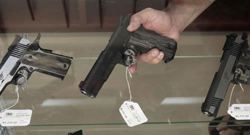 Dan Cartwright, co-owner of TDS   Guns, places a semi-automatic pistol on display at his store in   Rocklin, Calif., Friday, July 27, 2012. (AP Photo/Rich Pedroncelli)
